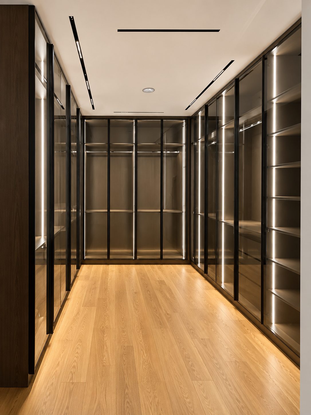 Walk-in wardrobe lined with smoked-glass doors and vertical strip lighting